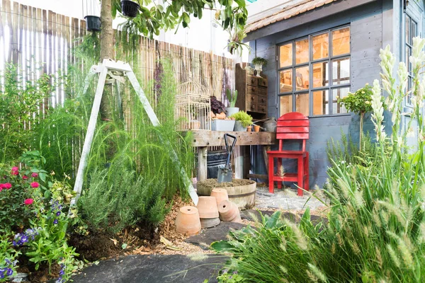 Silla roja en el jardín verde con acogedora casa. Jardín al aire libre . —  Fotos de Stock