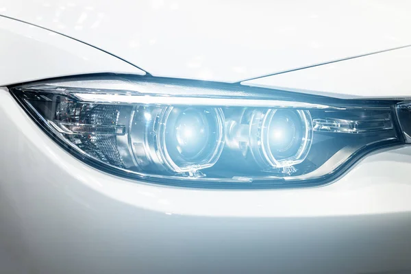 Luces delanteras de primer plano del coche moderno durante el encendido de la luz en la noche . — Foto de Stock