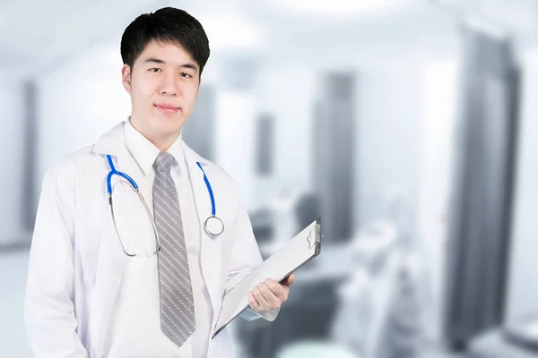 Asian doctor in ward holding a clipboard at modern hospital. Med