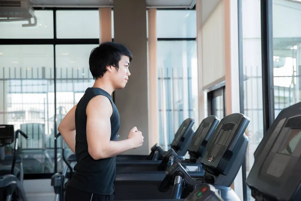 Азиатский юноша бегает на беговой дорожке в спортзале. Сотрудничество в области здравоохранения и спорта — стоковое фото