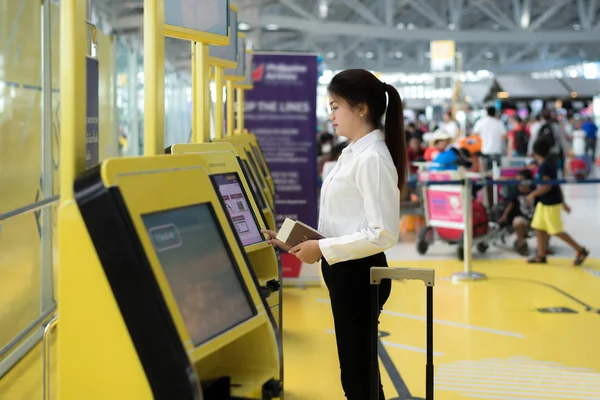Fiatal ázsiai üzletasszony segítségével saját check-in kioszknál, repülőtér. — Stock Fotó