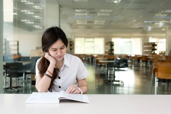 Asiática estudiante en uniforme lectura libro en aula en la universidad — Foto de Stock