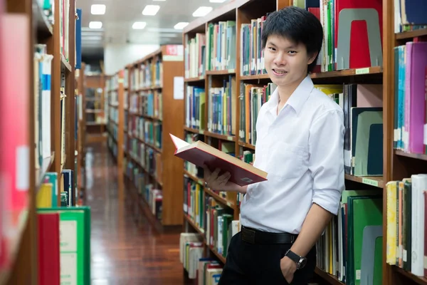 Estudante asiático em leitura uniforme na biblioteca da universidade — Fotografia de Stock