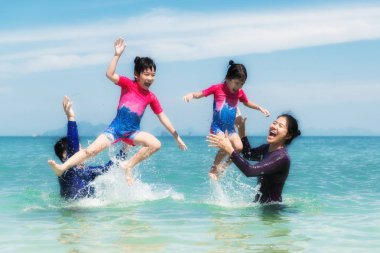Mutlu Asya ailesi okyanusta oynarken ve su p
