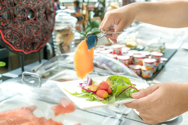 Gente agregando topping para ensalada de salmón ahumado en la línea de alimentos en ho —  Fotos de Stock
