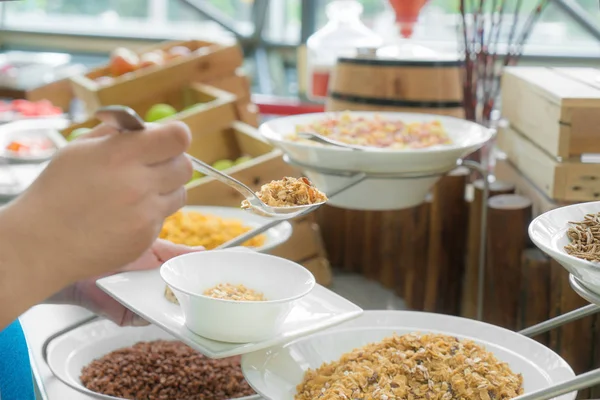 Colher de mão algum tipo de cereais em um café da manhã self-service em um — Fotografia de Stock