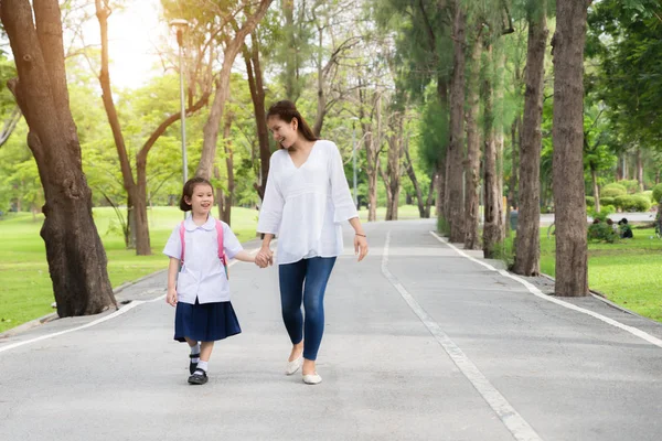 Asian mother and daughter student walking to school. Pupil stude