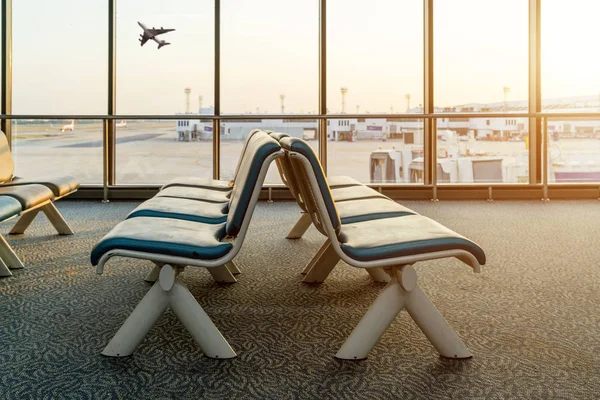 Sillas vacías en la sala de salida en el aeropuerto con taki avión —  Fotos de Stock