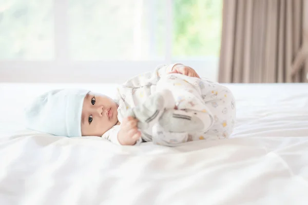 Portrait of 4 month Asian baby lying and playing foot on white b — Stock Photo, Image