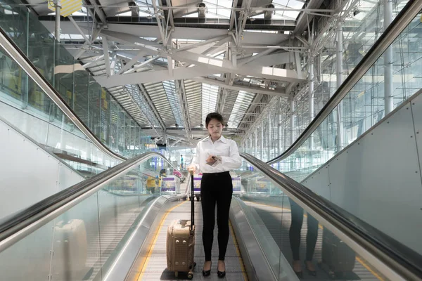 空気でエスカレーターを下りて荷物を持つアジアの若い実業家 — ストック写真
