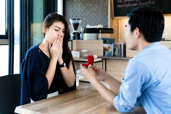 Asiatischer Mann zeigt seiner erstaunten Freundin einen Verlobungsring mit Diamanten — Stockfoto