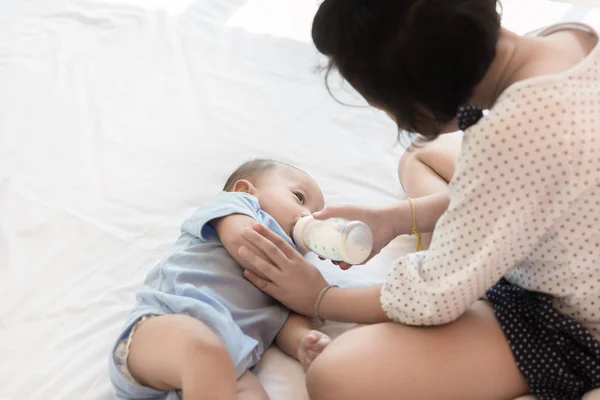 Asian sister is feeding her little brother and he drinks milk us — Stock Photo, Image