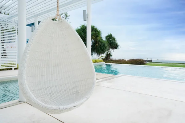 Entspannender weißer Rattan-Hängesessel am Pool mit Meerblick — Stockfoto