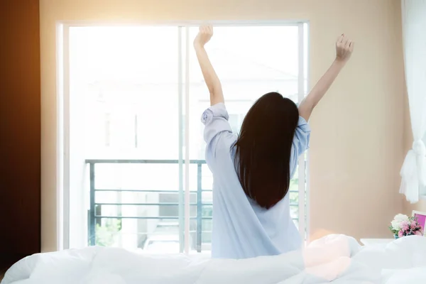 Азиатская женщина сидит у окна, растягиваясь на кровати после ва — стоковое фото