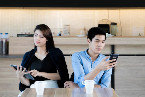 Asian couple looking at their mobile phone while on a date in ca