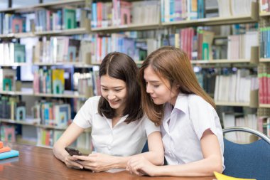 Tablo ve READI oturan mutlu iki genç Asyalı kız öğrenci