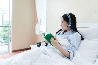 Okuma ve dinleme cep telefonu müzik oynamak için Asyalı genç kadın