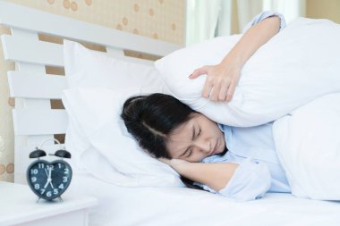 Genç güzel Asyalı kadın yatakta alarm cl acı yalan