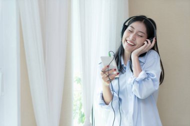 Genç Asyalı kadın yatak odasında müzik dinlerken kulaklık ile 