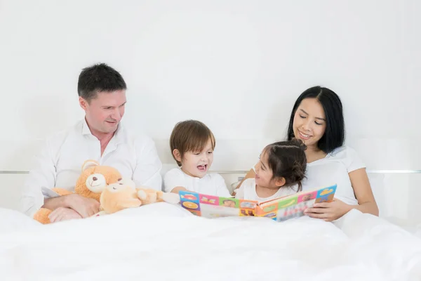 Asiático hermanos y asiático hija lectura libro juntos en cama i — Foto de Stock