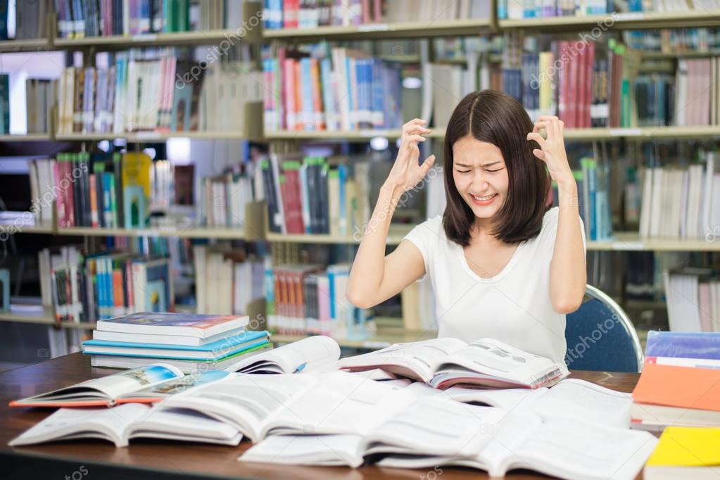 Young Asian student under mental pressure while reading book pre
