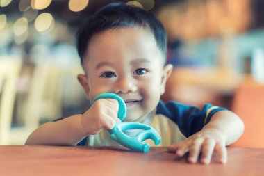 9 months old Asian baby boy sucking his rubber bite toy for reli clipart