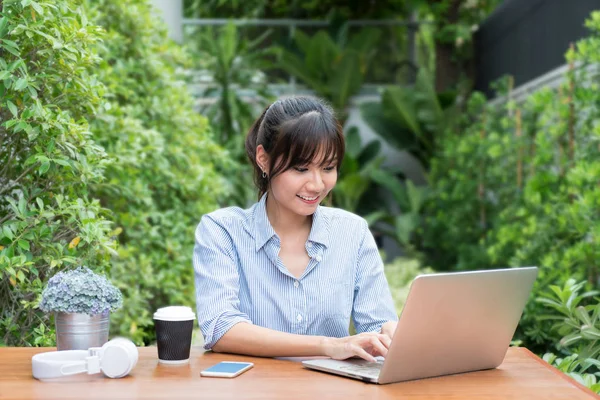 Азіатський жінка в усміхнені обличчя, використовуючи ноутбук, на робочому місці в дерево Гар — стокове фото