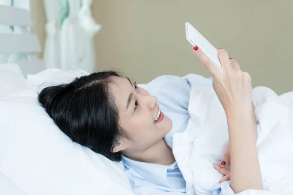Piękne Azjatki nastolatek kobieta leżąc w łóżku biały i za pomocą p — Zdjęcie stockowe