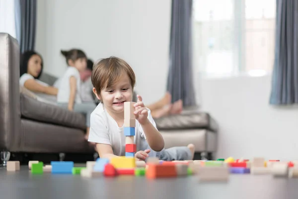 Asiático chico jugando madera juguete en sala de estar con padre, madre un — Foto de Stock