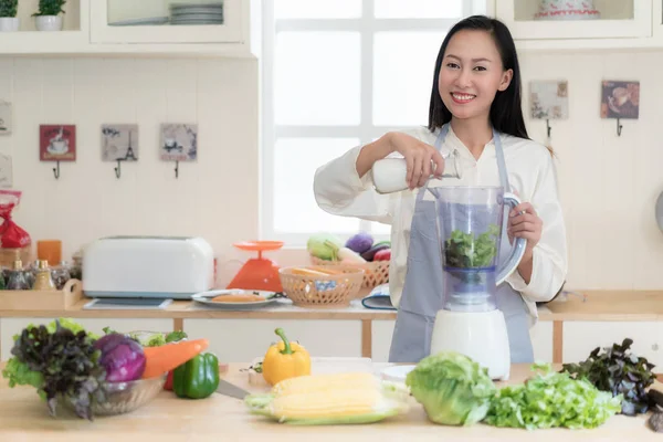 Vegetable smoothie. Asian woman making green smoothies with blen