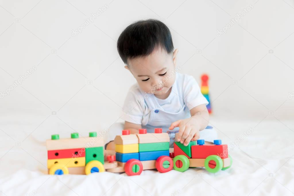 Adorable Asian baby boy 9 months sitting on bed and playing with