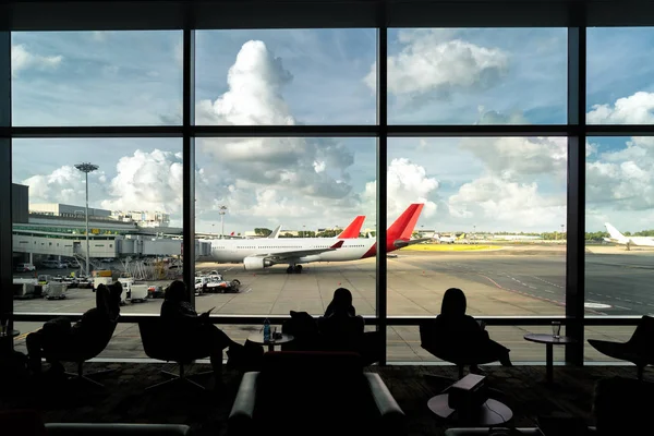 Silueta de pasajero esperando vuelo para viajar en salón en un —  Fotos de Stock