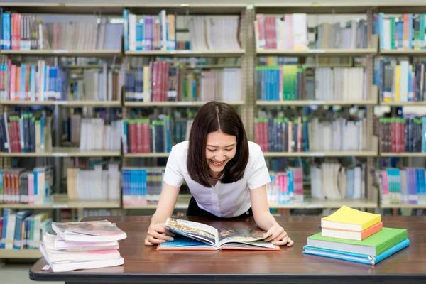 Cheerful female Asian student reading book during break between — Stock Photo, Image
