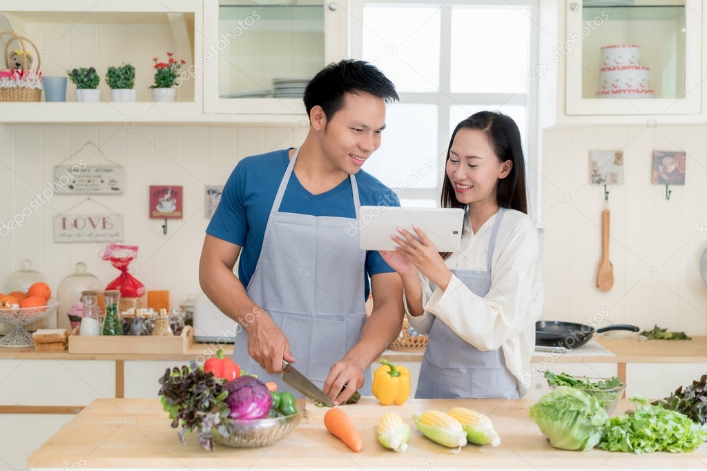 Asian beautiful young husband and wife searching menu recipe in 