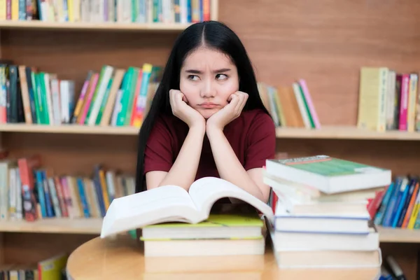 Asijské žena student nudné čtení knih v knihovně se spoustou — Stock fotografie
