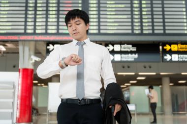 Asya genç işadamı saatini Havaalanı önünde bakarak