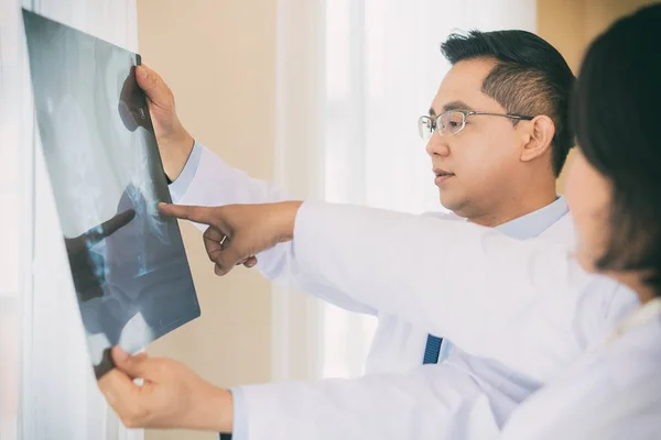 Zwei Arzt sprechen und untersuchen Röntgenfilm über Ergebnis und bac — Stockfoto