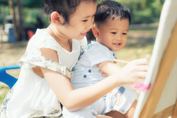 Asiático pequeño niño y hermana dibujar juntos en parque. Niños pintando — Foto de Stock