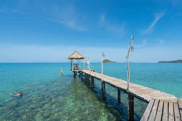 Turisti che fanno snorkeling in acque cristalline turchesi vicino a resort tropicale — Foto Stock