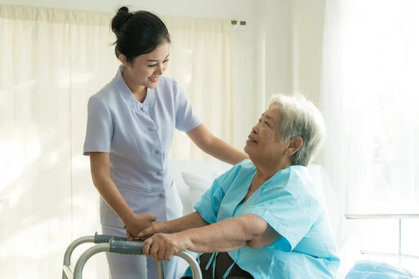 Asiatique jeune infirmière soutenir patient âgé femme handicapée en u — Photo