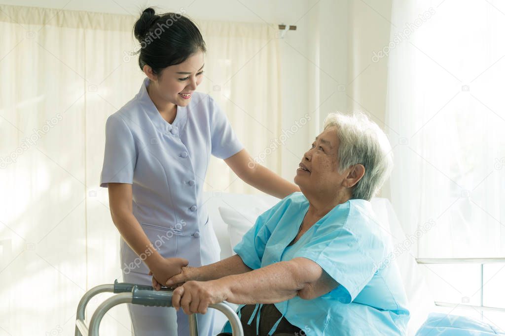 Asian young nurse supporting elderly patient disabled woman in u