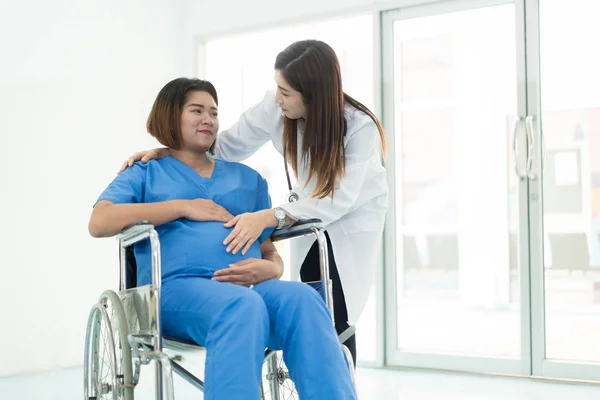 アジアの女性の車椅子の若い妊婦に話す医師 — ストック写真