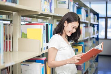 Asyalı öğrenci Üniversitesi'nde kütüphanede okuma. Öğrenci mutlu