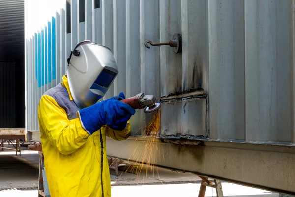 Промышленный рабочий с шлифовальным металлом для ремонта конструкции контейнера — стоковое фото