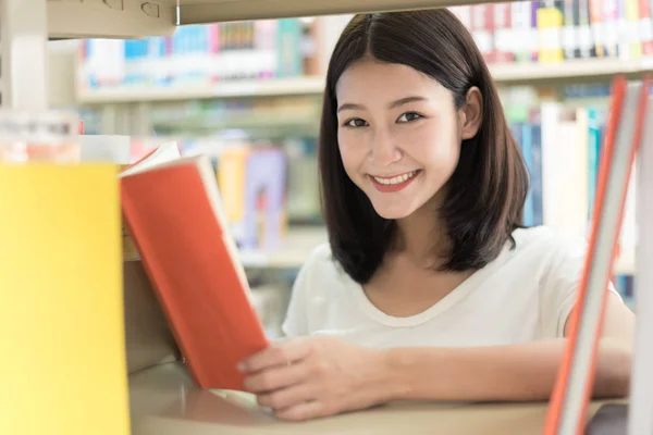 Estudiante asiático leyendo en la biblioteca de la universidad. Estudiante feliz — Foto de Stock