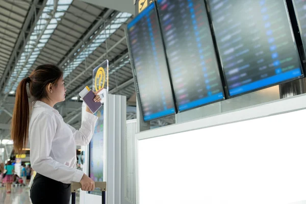 Asiatische junge Frau auf internationalem Flughafen schaut sich den Flug an — Stockfoto