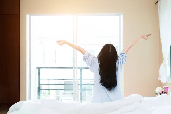Задний вид азиатской женщины растягивается в постели после пробуждения, поднимаясь — стоковое фото