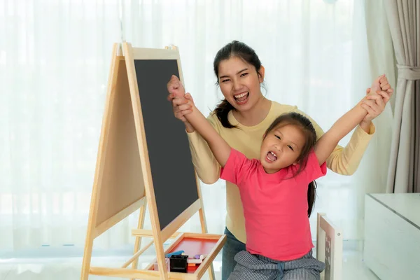 Happy successful Asian kindergarten student and her mother hands