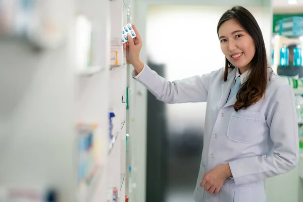 Ázsiai fiatal nő gyógyszerész egy szép barátságos mosoly pick c — Stock Fotó