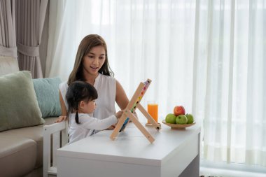 Mutlu Asya genç anne ve kızı abaküs ile oynarken, erken